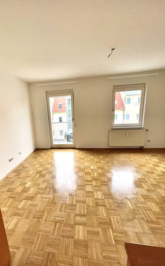 Wohnraum mit offener Küche und Ausgang auf den Balkon